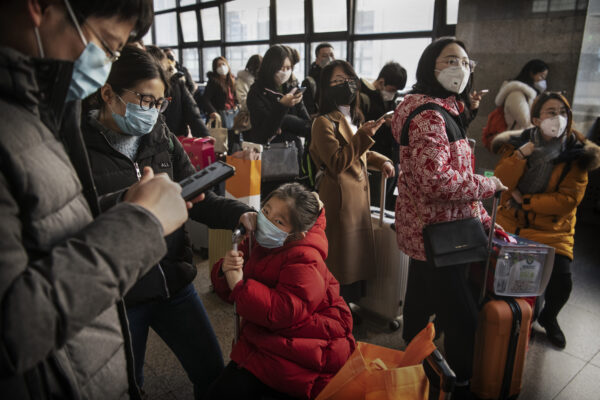 Les voyageurs chinois portent des masques de protection alors qu'ils attendent avant de monter à bord d'un train avant le festival annuel du printemps dans une gare de Pékin, en Chine, le 23 janvier 2020. (Kevin Frayer/Getty Images)