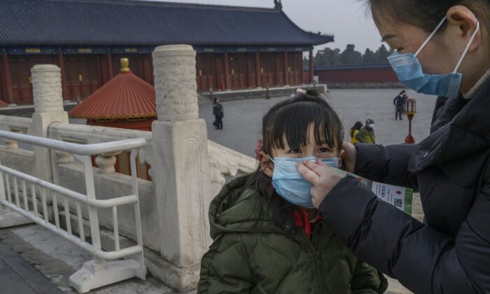 Une jeune visiteuse chinoise porte un masque de protection alors qu'elle visite le terrain presque vide du Temple du Ciel à Pékin, en Chine, le 27 janvier 2020. (Kevin Frayer/Getty Images)