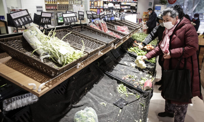 Une habitante porte un masque pour acheter des légumes au marché de Wuhan, dans la province de Hubei, en Chine, le 23 janvier 2020. Les vols, les trains et les transports publics, y compris les bus, le métro et les traversiers, ont été temporairement fermés, et les autorités ont demandé aux habitants de rester en ville afin d'aider à stopper l'épidémie d'une souche de coronavirus. (Getty Images)