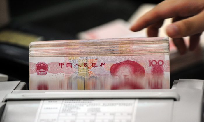 Un employé de banque chinois utilise une machine pour compter les piles de billets de 100 yuans pour un client d'une banque à Hefei, dans la province d'Anhui, en Chine, le 14 octobre 2010. (STR/AFP/Getty Images).