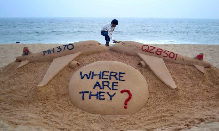 L'artiste indien Sudarsan Pattnaik donne la touche finale à sa sculpture de sable représentant deux avions disparus, Air Asia QZ8501 et Malayasia Airlines MH370 sur la plage de Golden Sea Beach, à Puri, à l'est de Bhubaneswar, dans une photo de dossier. (STRDEL/AFP/Getty Images)