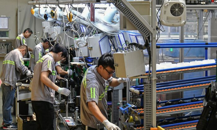 Le 15 mai 2019, des employés travaillent sur une chaîne de production de climatisation automobile dans une usine de Yantai, dans la province orientale du Shandong, en Chine. (STR/AFP via Getty Images)