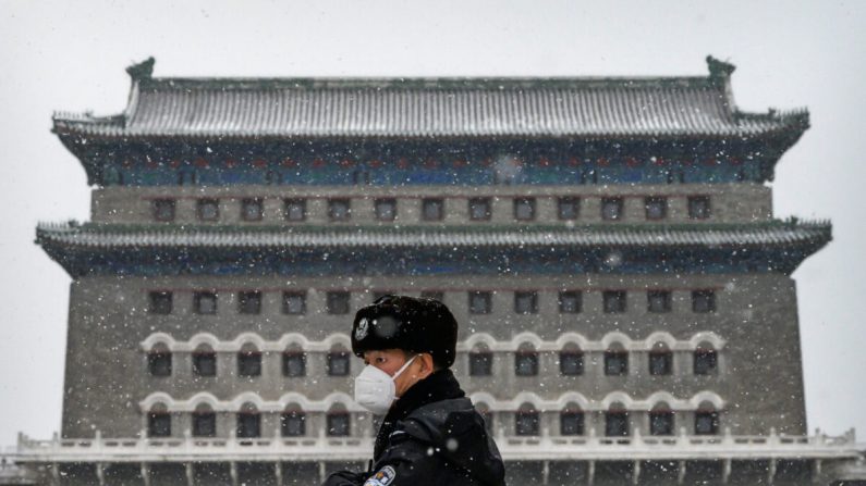 Un policier chinois porte un masque de protection alors qu'il monte la garde devant la porte Qianmen lors d'une chute de neige dans une rue commerciale vide et fermée à Pékin, en Chine, le 5 février 2020. (Kevin Frayer/Getty Images)