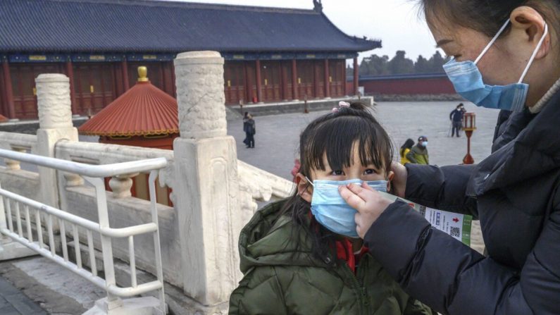 Une femme chinoise met un masque de protection sur sa fille alors qu'elle visite le Temple du Ciel à Pékin, en Chine, qui est resté ouvert pendant la fête du Nouvel An chinois et du Festival du printemps, le 27 janvier 2020. (Kevin Frayer/Getty Images)