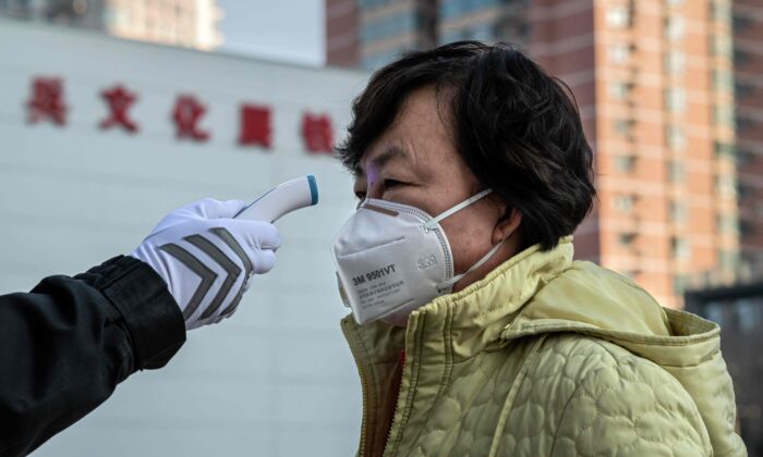 Un agent de sécurité vérifie la température d'une femme portant un masque de protection à l'entrée d'un parc à Pékin, en Chine, le 31 janvier 2020. (NICOLAS ASFOURI/AFP via Getty Images)