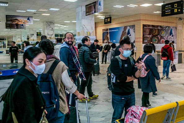 Les passagers, portant des masques, récupèrent leurs bagages alors qu'ils se préparent à quitter l'aéroport international d'Assouan dans la ville égyptienne, à environ 920 km au sud de la capitale, Le Caire, le 2 février 2020. (Photo : KHALED DESOUKI/AFP via Getty Images)