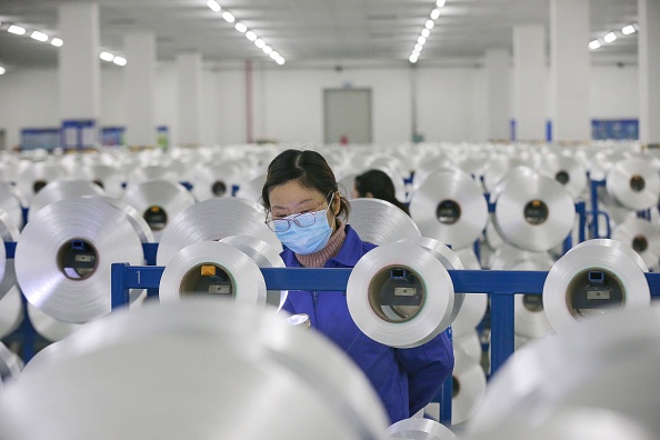 -Un employé chinois portant un masque facial produit des matériaux qui seront utilisés sur des combinaisons de protection dans une usine textile de Nantong, dans la province orientale du Jiangsu en Chine. Photo par STR / AFP via Getty Images.