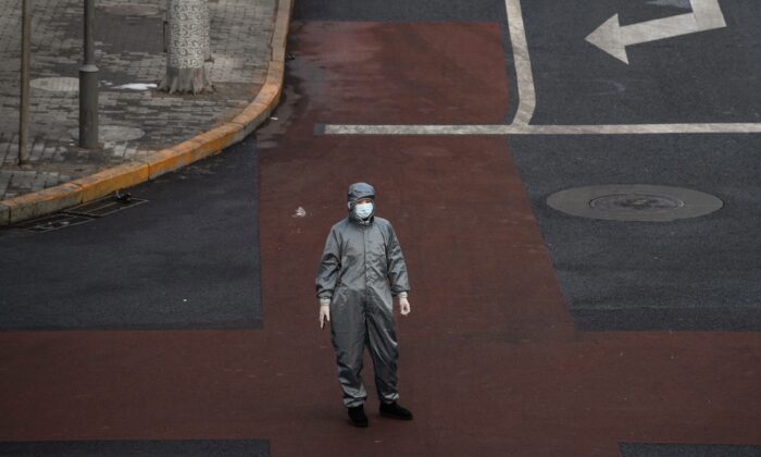 Une femme chinoise porte un vêtement de protection et un masque en attendant de traverser l'intersection d'une rue presque vide à Pékin, en Chine, le 8 février 2020. (Kevin Frayer / Getty Images)
