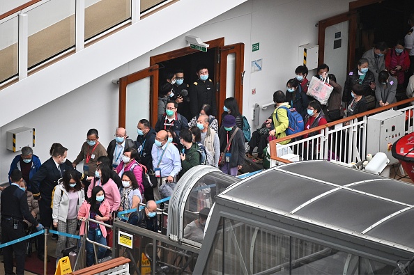 -Des passagers font la queue pour enfin débarquer du navire de croisière World Dream au terminal de croisière Kai Tak à Hong Kong le 9 février 2020, où 3600 personnes sont restées confinées à bord pendant des jours alors que les autorités effectuaient des contrôles de santé en raison de l'épidémie du nouveau coronavirus en Chine continentale. Photo de Philip FONG / AFP via Getty Images.