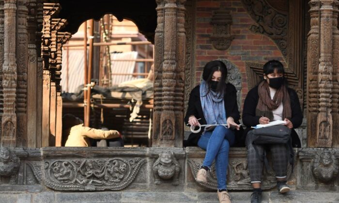 Des résidents portant des masques de protection sont assis à Patan Durbar Square à Katmandou, au Népal, le 10 février 2020. (Prakash Mathema/AFP via Getty Images)