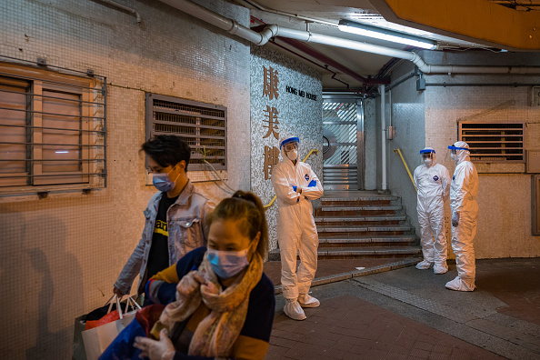 -Des résidents quittent Hong Mei House, des fonctionnaires portent un équipement de protection et montent la garde devant une entrée, à Cheung Hong Estate le 11 février 2020 à Hong Kong, Chine. Photo par Billy HC Kwok / Getty Images.