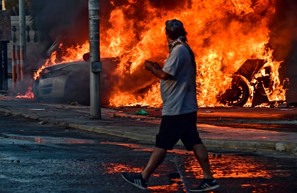 -Des voitures en flammes à l'extérieur de l'hôtel O'Higgins qui ont été incendiées par des manifestants, le 23 février 2020, lors du festival de musique de Vina del Mar. Photo de MARTIN BERNETTI / AFP via Getty Images.