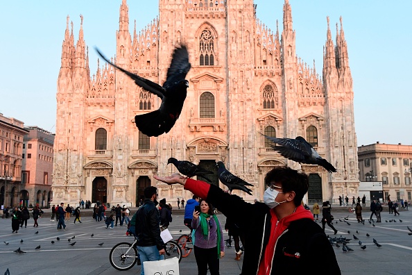 -Un homme portant un masque protecteur joue avec des pigeons sur la Piazza del Duomo, dans le centre de Milan, le 24 février 2020 à la suite des mesures de sécurité prises dans le nord de l'Italie contre le COVID-19, le nouveau coronavirus. Photo de MIGUEL MEDINA / AFP via Getty Images.