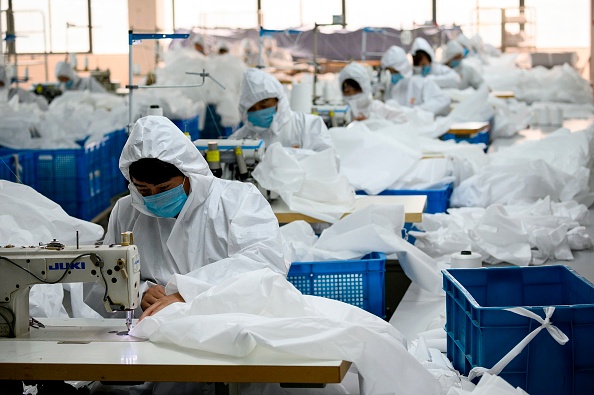 Cette photo prise le 28 février 2020 montre des travailleurs cousant dans une usine fabriquant des combinaisons à utiliser pour se protéger de l'épidémie de coronavirus COVID-19, à l'usine de confection de l'industrie du canard laid du Zhejiang à Wenzhou. Photo de NOEL CELIS / AFP via Getty Images.