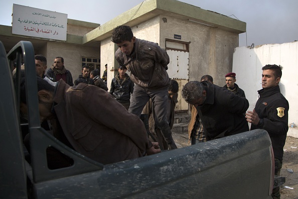 -Des membres de l'armée irakienne aident des djihadistes du groupe État islamique (EI) à monter dans une camionnette lorsqu'ils quittent la Maison de la Justice avant d'aller en prison le 6 décembre 2016 au sud de Mossoul. Photo GAILAN HAJI / AFP via Getty Images.