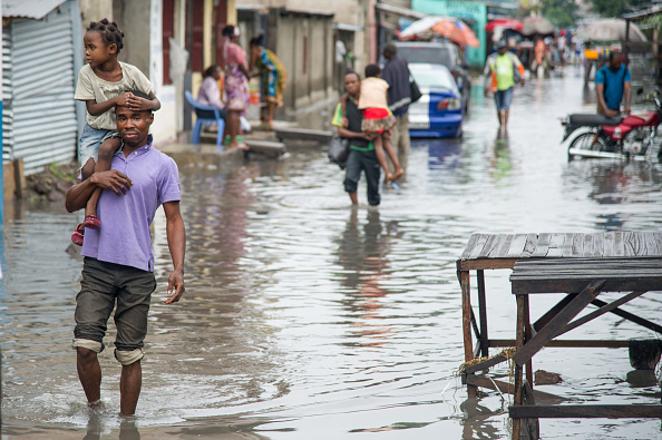 -Illustration- Un homme porte une jeune fille sur ses épaules alors qu'il marche dans une rue inondée du centre de Kinshasa, après que plusieurs quartiers de la ville ont été inondés à la suite d'une élévation brutale du niveau d'eau causée par une violente tempête. Photo JUNIOR KANNAH / AFP via Getty Images.