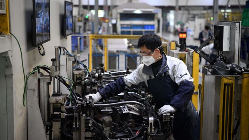 Un ouvrier portant un masque de protection travaille sur une chaîne de montage de sièges automobiles à l'usine Yanfeng Adient de Shanghai le 24 février 2020. (Noel Celis/AFP via Getty Images)