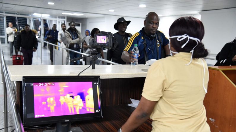 Un membre du personnel du Port Health Service se tient à côté d'un scanner thermique alors que les passagers arrivent à l'aéroport international Murtala Mohammed de Lagos, au Nigeria, le 27 janvier 2019. (Photo de PIUS UTOMI EKPEI/AFP via Getty Images)