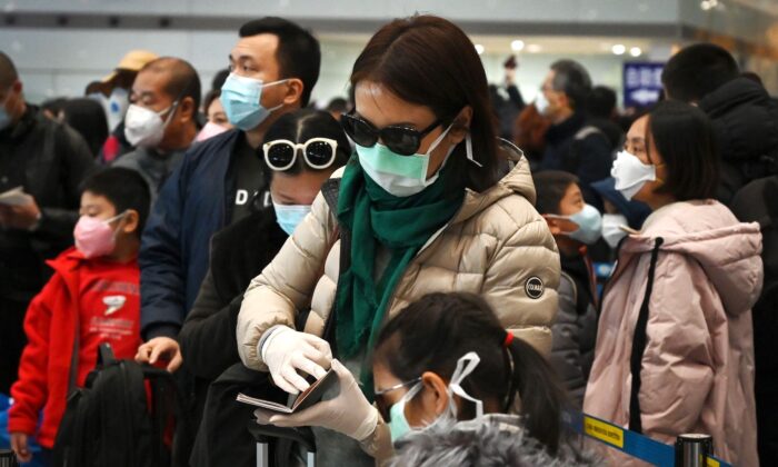 Une femme porte un masque et des gants de protection en attendant de passer à la douane à l'aéroport de Pékin le 1er février 2020. (Greg Baker/AFP via Getty Images)