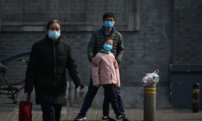 Un homme et une fille masqués attendent de traverser une rue à Pékin, en Chine, le 28 février 2020. (STR/AFP via Getty Images)