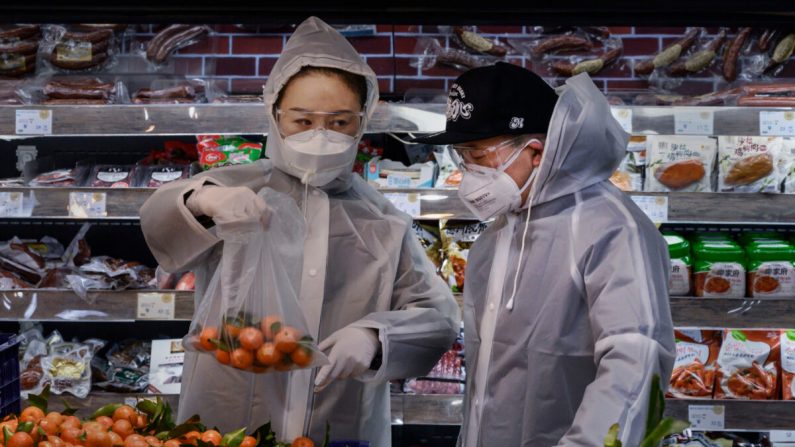 Un couple de Chinois porte des combinaisons en plastique et des masques de protection pour faire leurs courses dans un supermarché de Pékin, le 11 février 2020. (Kevin Frayer/Getty Images)