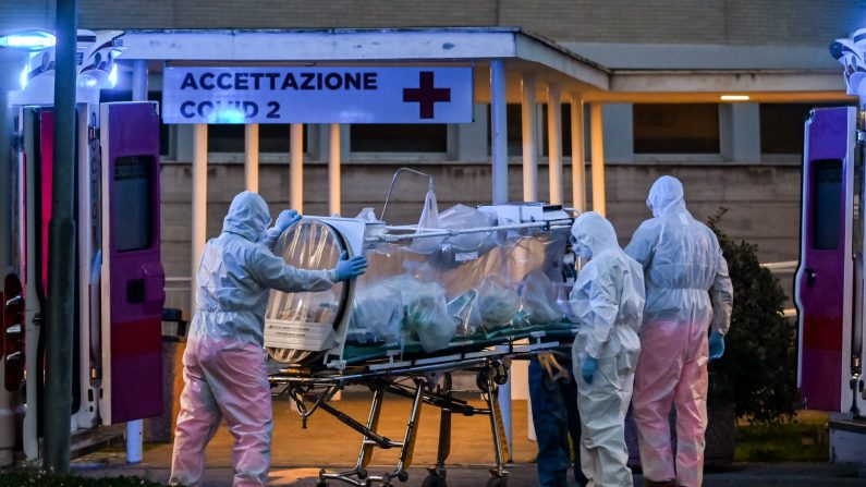 Le 16 mars 2020, des professionnels de la santé en combinaisons font entrer un patient en soins intensifs dans la nouvelle structure temporaire de l'hôpital Gemelli à Rome, en Italie. (Andreas Solaro/AFP via Getty Images) 