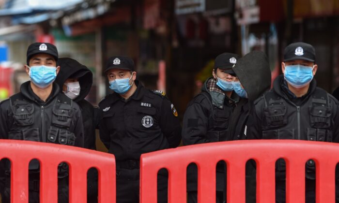 Des policiers et des agents de sécurité devant le marché en gros de fruits de mer de Huanan à Wuhan, le 24 janvier 2020. (HECTOR RETAMAL/AFP via Getty Images)