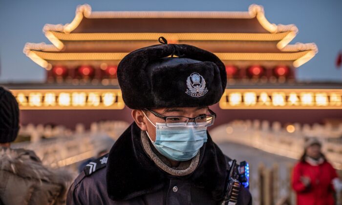 Un policier portant un masque de protection passe devant le portrait du défunt leader communiste Mao Zedong (non représenté sur la photo) à la Porte Tiananmen à Pékin le 23 janvier 2020. (NICOLAS ASFOURI/AFP via Getty Images)