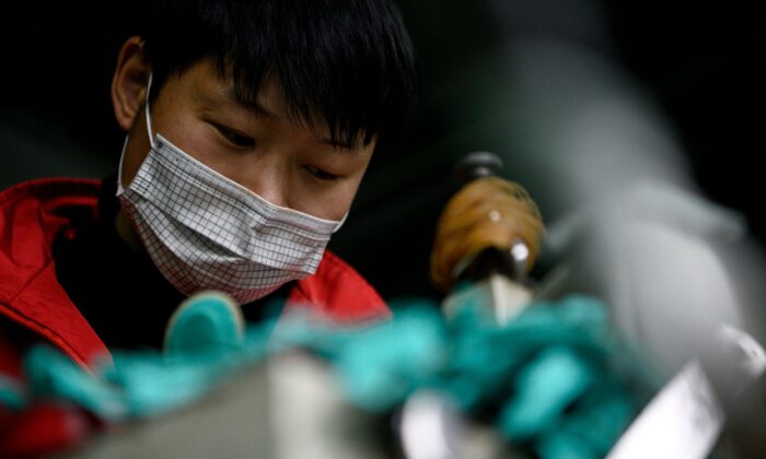 Un ouvrier portant un masque facial fabrique des semelles intérieures à l'usine Zhejiang Xuda Shoes Co. à Wenzhou, en Chine, le 27 février 2020. (NOEL CELIS/AFP via Getty Images)