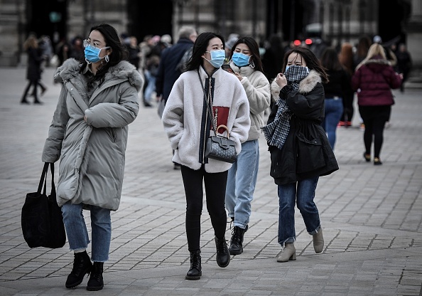 -Illustration- Des chinois portent un masque protecteur au milieu des craintes de la propagation du coronavirus COVID-19 dans le quartier de la Pyramide du Louvre le 28 février 2020 à Paris. Photo de STEPHANE DE SAKUTIN / AFP via Getty Images.