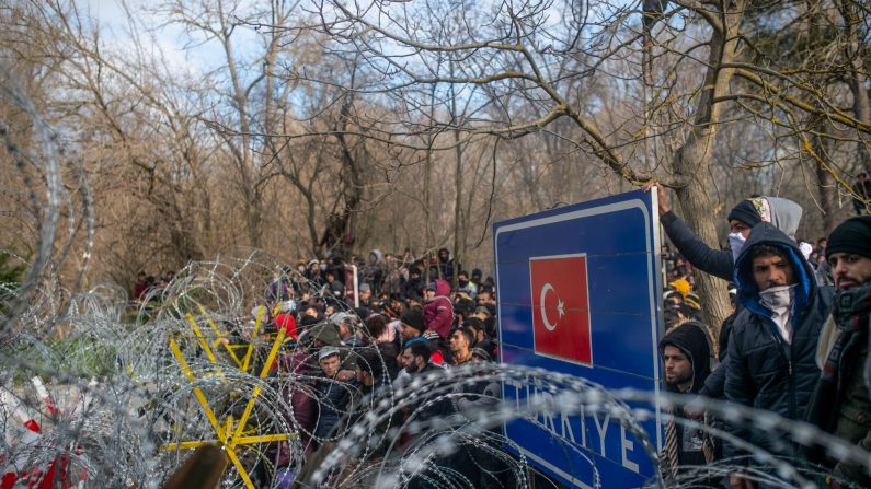 Des migrants se rassemblent derrière une clôture de barbelés dans la zone tampon à la frontière entre la Turquie et la Grèce à Pazarkule, dans le district d'Edirne. (Photo : BULENT KILIC/AFP via Getty Images)