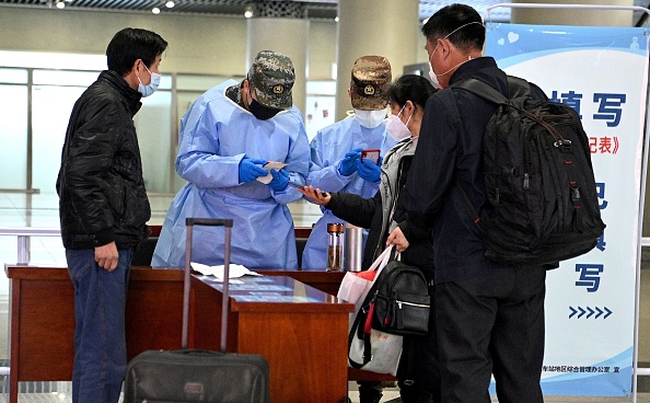 -Les passagers portant des masques faciaux font vérifier leurs antécédents de voyage à leur arrivée à la gare de Hefei, dans la province orientale de l'Anhui, en Chine, le 4 mars 2020. Photo de NOEL CELIS / AFP via Getty Images.