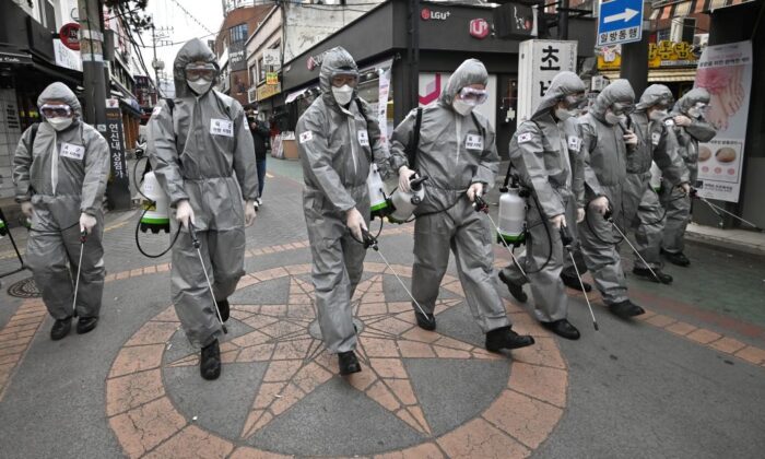 Des soldats sud-coréens portant des équipements de protection pulvérisent du désinfectant pour aider à prévenir la propagation du nouveau coronavirus, dans un quartier commercial de Séoul, en Corée du Sud, le 4 mars 2020. (Jung Yeon-je/AFP via Getty Images)