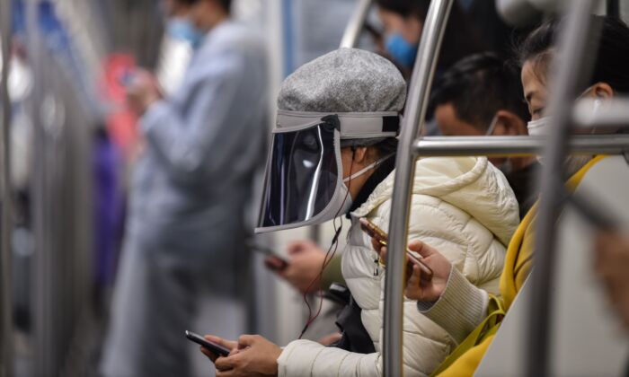 Une femme portant un masque plastique sur un masque de protection emprunte le métro de Shanghai, en Chine, le 5 mars 2020. (HECTOR RETAMAL/AFP via Getty Images)
