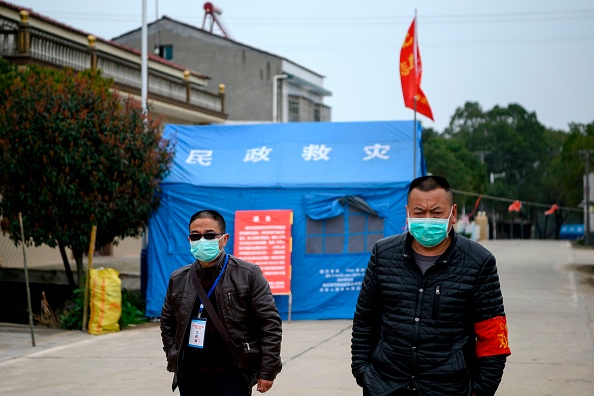 -Des résidents portent des masques faciaux pour se protéger contre le coronavirus COVID-19, un homme à un poste de contrôle à la frontière de Shishou au sud de la province du Hubei et du comté de Huarong dans la province du Hunan le 5 mars 2020. Photo de NOEL CELIS / AFP via Getty Images.