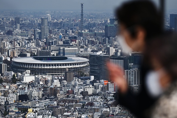 -Des personnes portant des masques faciaux regardent le nouveau stade de Tokyo, le principal site des Jeux olympiques de 2020, à Tokyo le 9 mars 2020. Photo de CHARLY TRIBALLEAU / AFP via Getty Images.