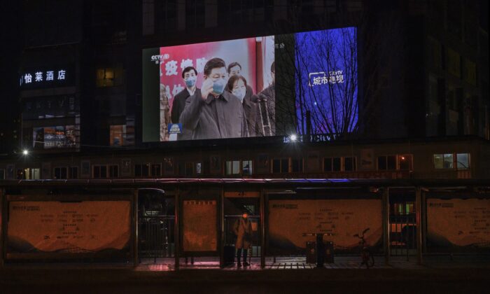 Un grand écran dans la rue montre le leader chinois Xi Jinping portant un masque de protection lors de sa visite à Wuhan, l'épicentre du coronavirus, au journal télévisé du soir de CCTV à Pékin le 10 mars 2020. (Kevin Frayer/Getty Images)