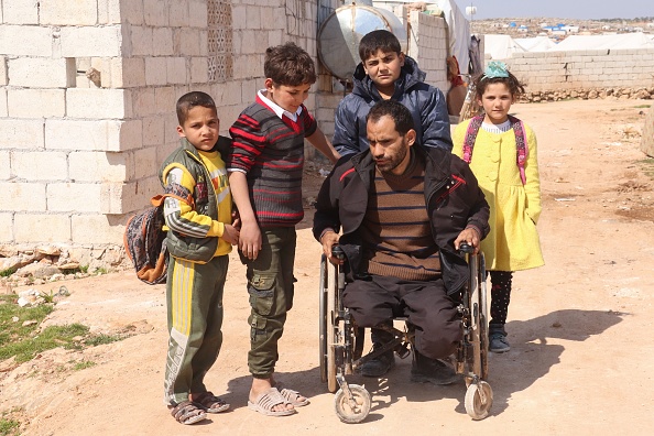 -Le syrien Ibrahim al-Ali est assisté par ses enfants, au camp de Deir Hassan pour personnes déplacées où ils résident, dans la campagne nord d'Idlib, près de la frontière turque, le 7 mars 2020. Photo par AHMAD AL-ATRASH / AFP via Getty Images.