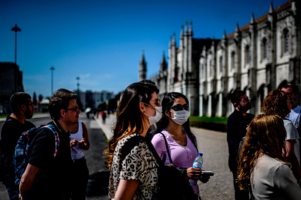 Des touristes portant des masques font la queue pour entrer dans le monastère des Hiéronymites à Lisbonne le 12 mars 2020.(Photo : PATRICIA DE MELO MOREIRA/AFP via Getty Images)