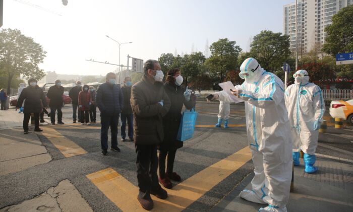 Le personnel médical (en combinaison de protection) examine les patients qui se sont rétablis du coronavirus COVID-19 alors qu'ils arrivent pour être testés à nouveau dans un hôpital de Wuhan, en Chine, le 14 mars 2020. (STR/AFP via Getty Images)