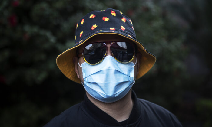 Un homme porte un masque à une barricade improvisée destinée au contrôle des allées et venus des visiteurs, dans un complexe résidentiel à Wuhan, en Chine, le 14 mars 2020. (Stringer/Getty Images)