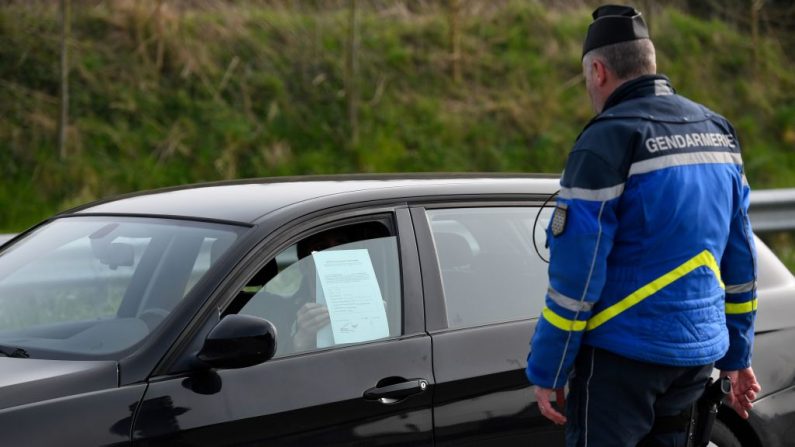 Un gendarme français vérifie un document de mobilité d'un conducteur dans le cadre de l'action de contrôle d'un verrouillage strict en France pour arrêter la propagation du coronavirus, le 20 mars 2020 (Photo by DAMIEN MEYER/AFP via Getty Images)