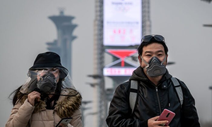 Des personnes portant des masques marchent dans le parc olympique de Pékin le 24 mars 2020. (Nicolas Asfouri/AFP via Getty Images)
