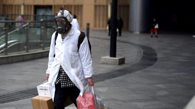 Un homme portant un masque transporte des articles qu'il a achetés dans un supermarché à Wuhan, en Chine, le 30 mars 2020. (NOEL CELIS/AFP via Getty Images)