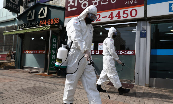 Des soldats sud-coréens, portant des équipements de protection, pulvérisent une solution antiseptique pour la protection contre le coronavirus le long d'une rue du district de Gangnam à Séoul, en Corée du Sud, le 9 mars 2020. (Chung Sung-Jun/Getty Images)