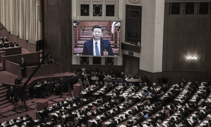Le dirigeant chinois Xi Jinping vu sur un grand écran au-dessus des délégués alors qu'il se joint à une session de l'Assemblée nationale populaire tenue au Grand palais du Peuple à Pékin, le 11 mars 2018. (Kevin Frayer/Getty Images)