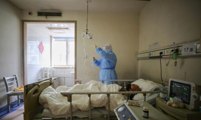 Un membre du personnel médical vérifie les médicaments utilisés par un patient atteint de COVID-19 à l'hôpital de la Croix-Rouge de Wuhan, dans la province de Hubei, en Chine, le 11 mars 2020 (STR/AFP via Getty Images)