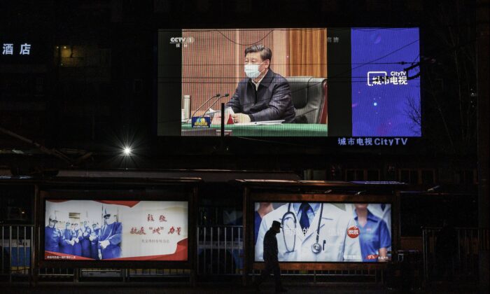 Un grand écran montre le leader chinois Xi Jinping portant un masque de protection lors de sa visite à Wuhan, au journal télévisé du soir de CCTV, le 10 mars 2020. (Kevin Frayer/Getty Images)