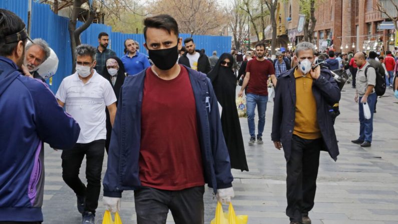 Des Iraniens, certains portant des masques de protection, marchent devant le grand bazar de la capitale Téhéran, pendant la crise de la pandémie du virus du PCC, le 18 mars 2020. (-/AFP via Getty Images)