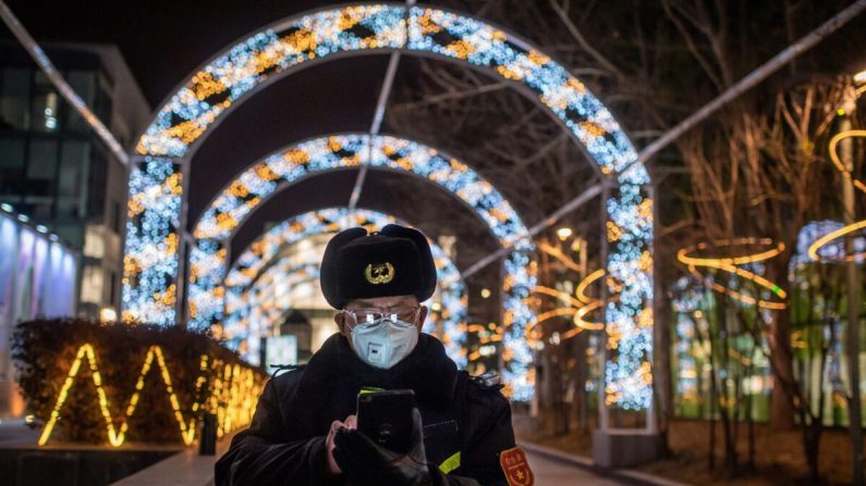 Un agent de sécurité consulte son téléphone portable alors qu'il surveille l'entrée d'un centre commercial quasiment vide de Pékin, en Chine, le 27 février 2020. (NICOLAS ASFOURI/AFP via Getty Images)